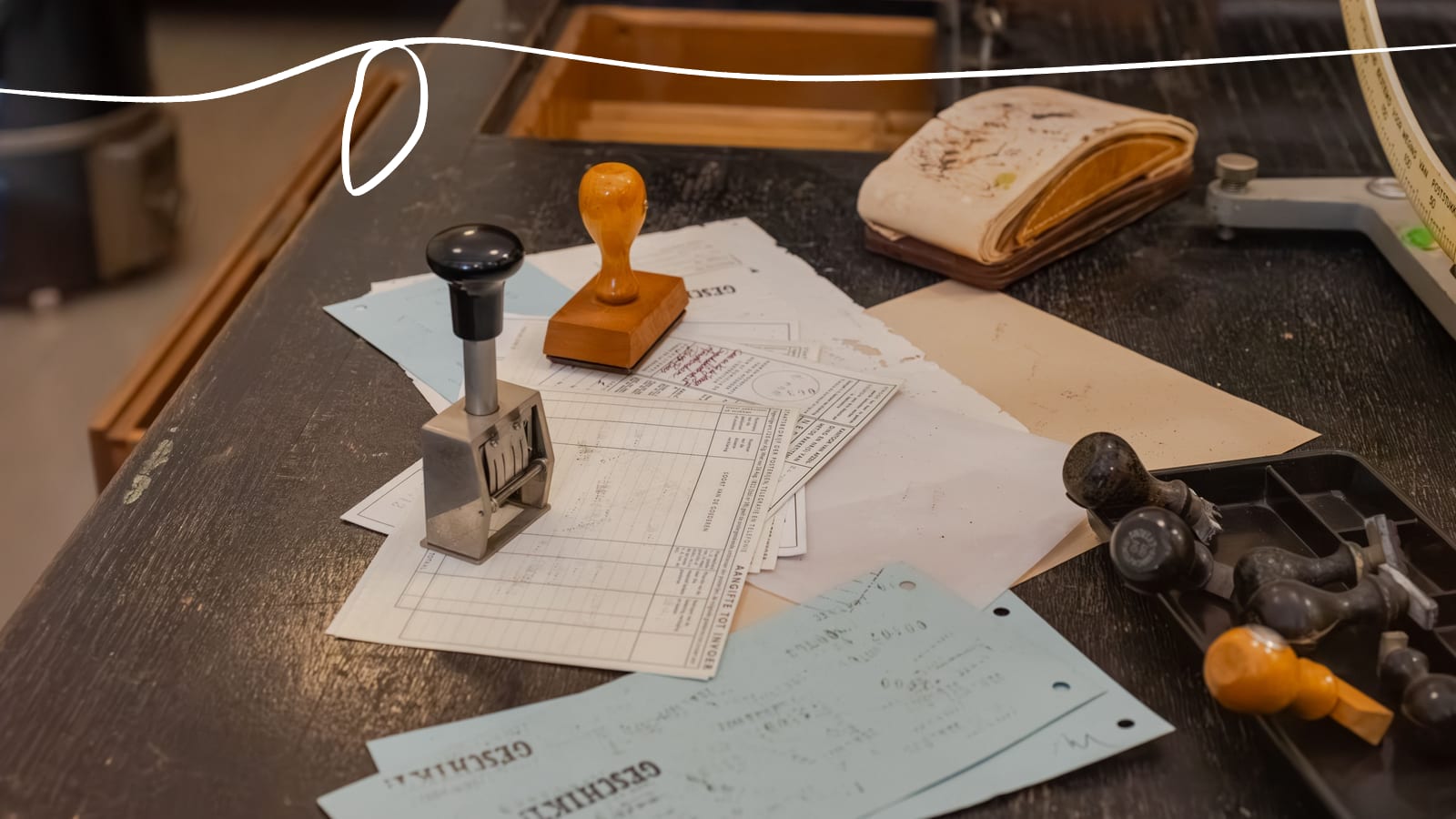 Rubber stamps and a date stamp on a pile of official forms on a worn registry desk