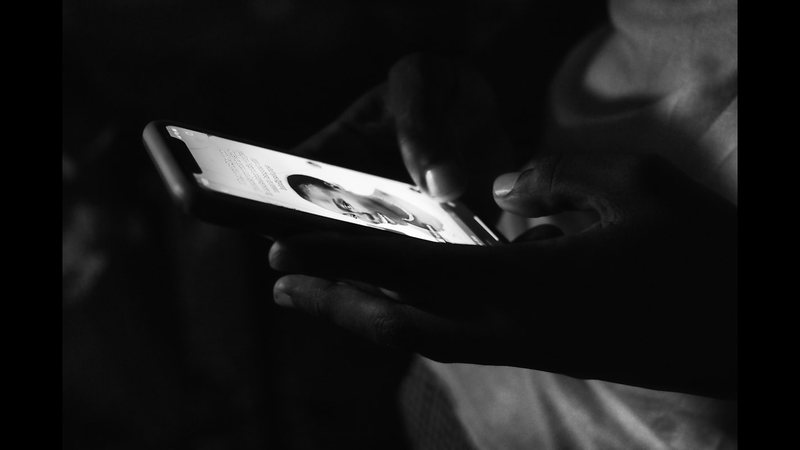 A person holding a smartphone and reading a message carefully in low light